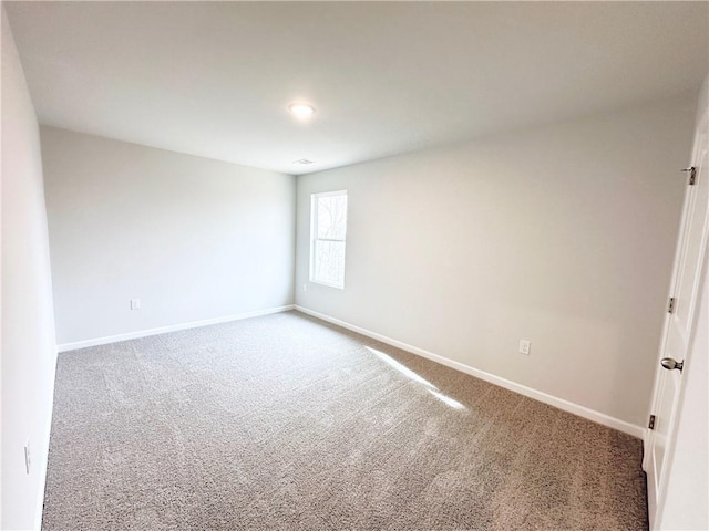 carpeted spare room featuring baseboards