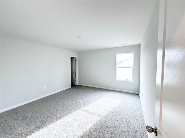 carpeted spare room featuring visible vents and baseboards