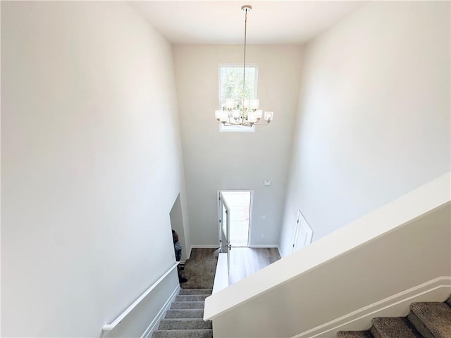 stairway featuring baseboards and a chandelier