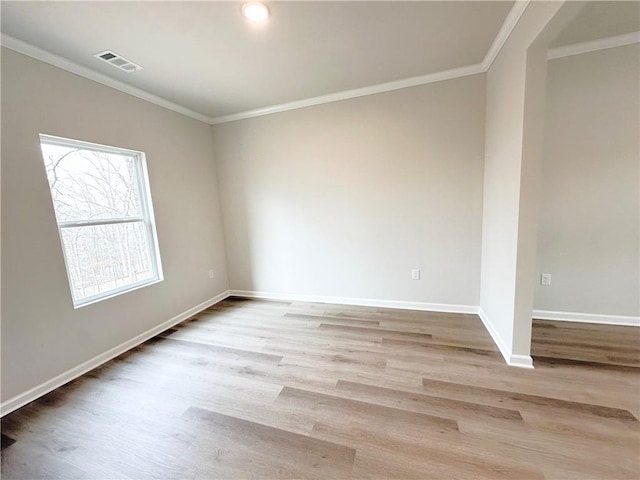 empty room featuring visible vents, baseboards, wood finished floors, and crown molding