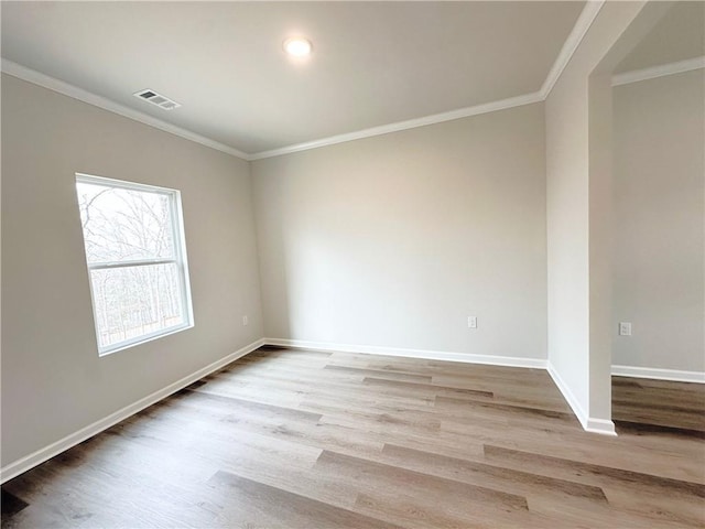 unfurnished room with visible vents, crown molding, baseboards, and wood finished floors