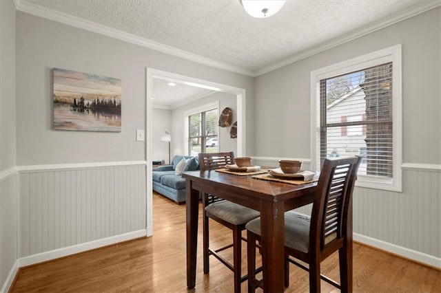 dining room with crown molding, a textured ceiling, and light hardwood / wood-style flooring