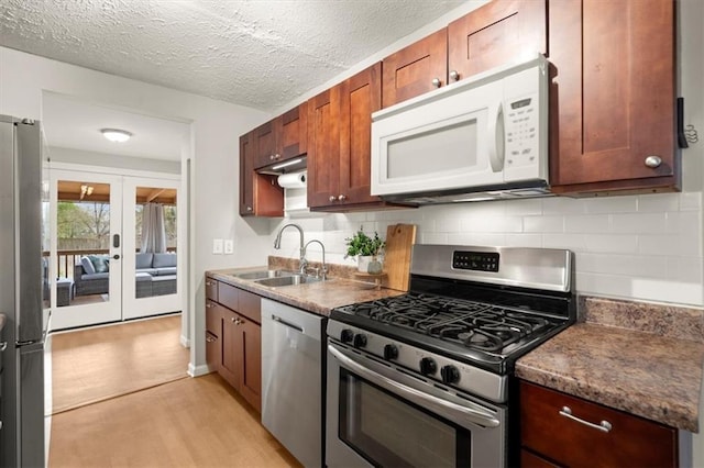 kitchen with sink, appliances with stainless steel finishes, a textured ceiling, decorative backsplash, and french doors