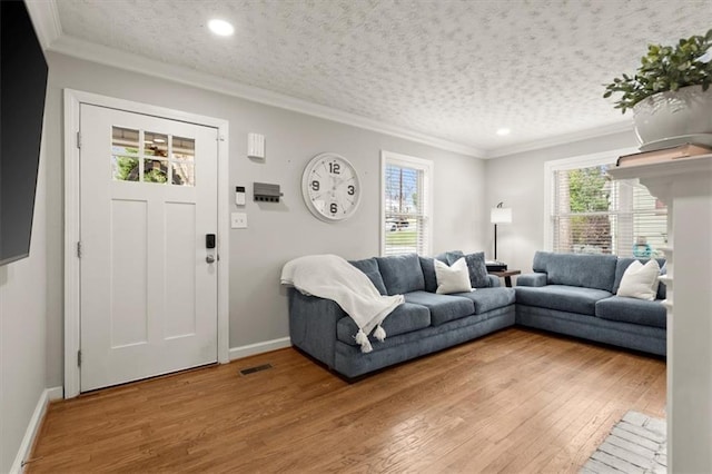 living room with hardwood / wood-style flooring, ornamental molding, plenty of natural light, and a textured ceiling