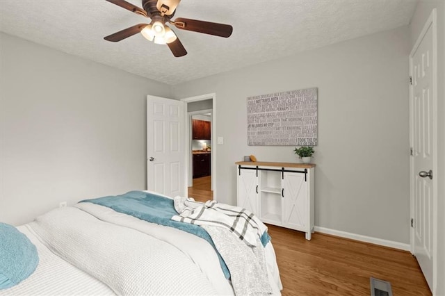 bedroom featuring hardwood / wood-style floors, a textured ceiling, and ceiling fan