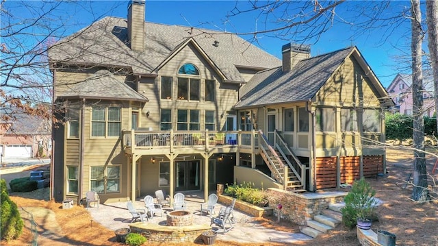 back of house featuring stairs, a chimney, a sunroom, and an outdoor fire pit