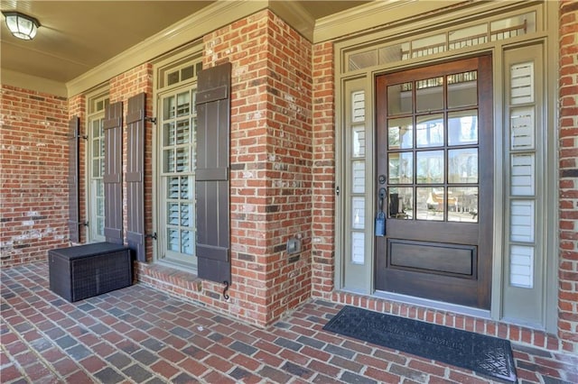 doorway to property with brick siding and covered porch