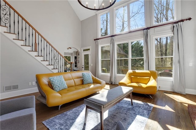 living room with visible vents, wood finished floors, an inviting chandelier, baseboards, and stairs