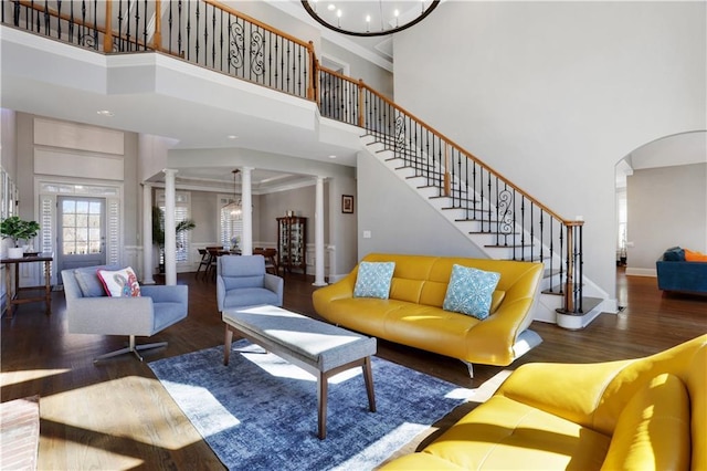 living area with baseboards, stairway, wood finished floors, a notable chandelier, and ornate columns