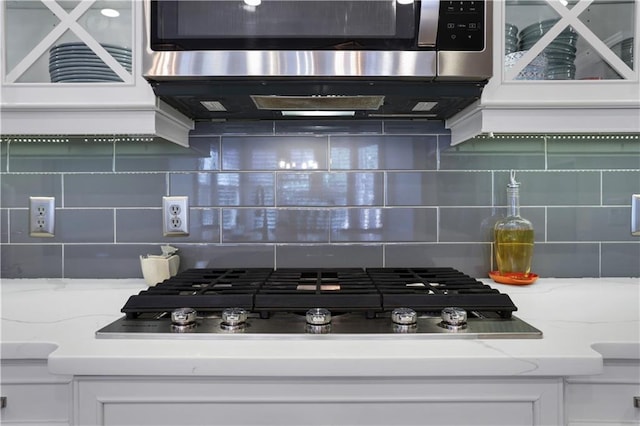 kitchen with light stone countertops, tasteful backsplash, appliances with stainless steel finishes, and white cabinets