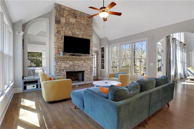 living area with ceiling fan, a fireplace, built in shelves, and wood finished floors