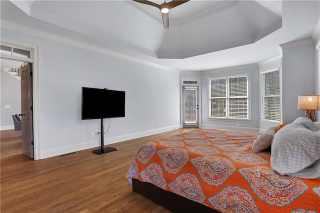 bedroom with ornamental molding, a tray ceiling, and wood finished floors