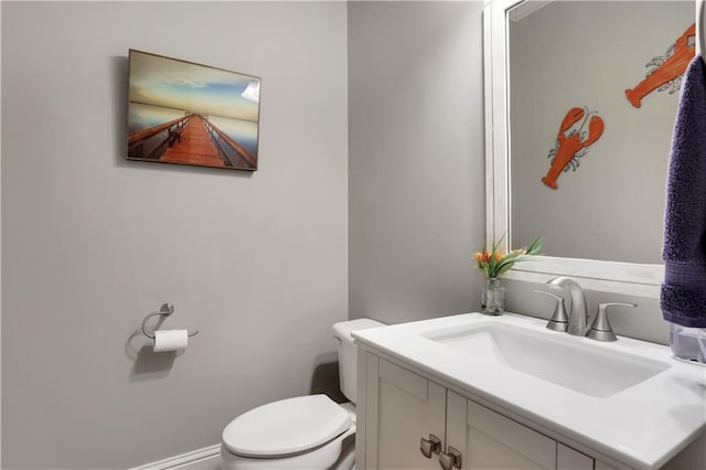 bathroom featuring baseboards, toilet, and vanity