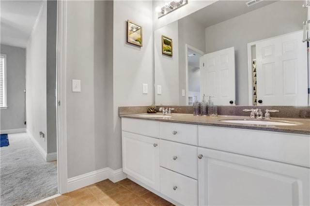 bathroom with double vanity, baseboards, tile patterned floors, and a sink