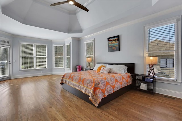 bedroom featuring visible vents, a raised ceiling, baseboards, and wood finished floors