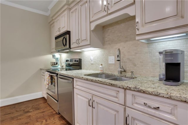 kitchen featuring dark wood-style flooring, a sink, appliances with stainless steel finishes, crown molding, and backsplash