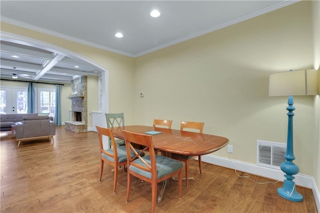 dining room with a fireplace, wood finished floors, visible vents, and coffered ceiling