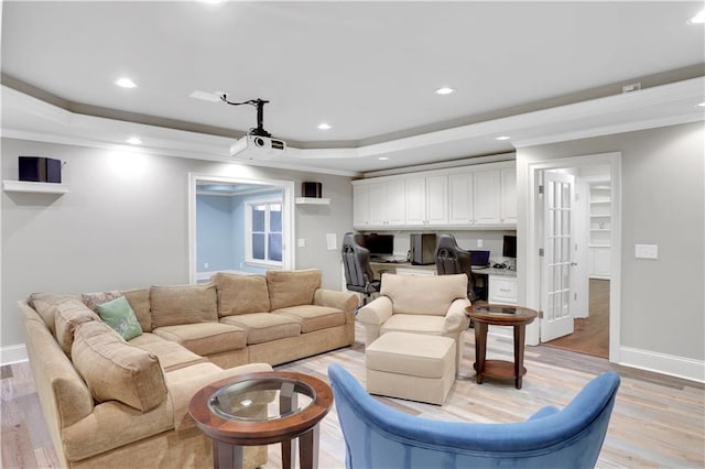 living area featuring a tray ceiling, built in desk, recessed lighting, crown molding, and light wood finished floors