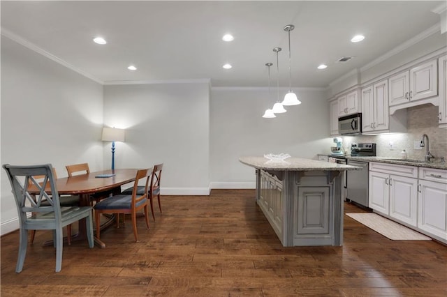 kitchen with visible vents, dark wood-style flooring, a sink, stainless steel appliances, and backsplash