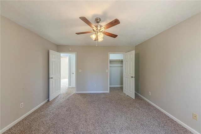 unfurnished bedroom with light colored carpet, a closet, a spacious closet, and ceiling fan