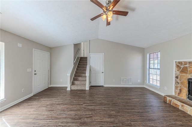 unfurnished living room with ceiling fan, a stone fireplace, dark hardwood / wood-style flooring, and lofted ceiling