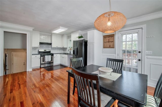 dining space featuring hardwood / wood-style flooring, ornamental molding, and sink