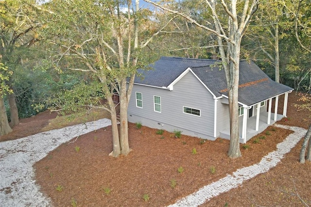 view of home's exterior featuring a shingled roof, crawl space, and gravel driveway