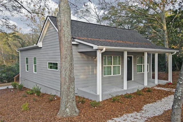 view of home's exterior featuring covered porch and a shingled roof