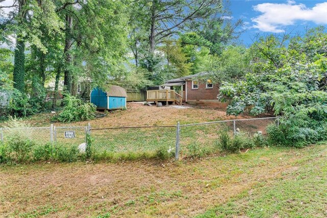 view of yard featuring a wooden deck and a storage shed