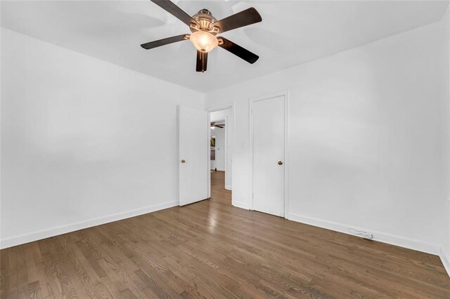 empty room with ceiling fan and dark hardwood / wood-style flooring