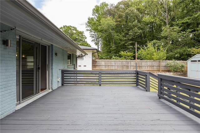 wooden deck with fence, a storage unit, and an outbuilding