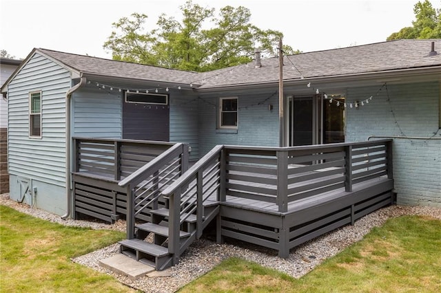 back of house with a lawn, a wooden deck, a shingled roof, and brick siding