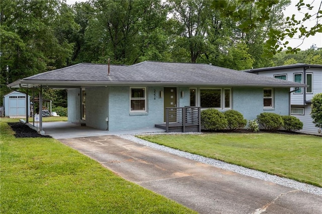 view of front of home with a front lawn, brick siding, a storage shed, an outbuilding, and concrete driveway