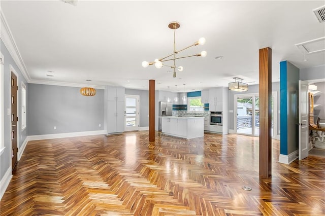 unfurnished living room featuring a sink, baseboards, visible vents, and a chandelier