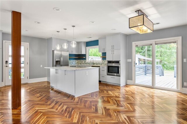 kitchen featuring a kitchen island, baseboards, appliances with stainless steel finishes, and a sink