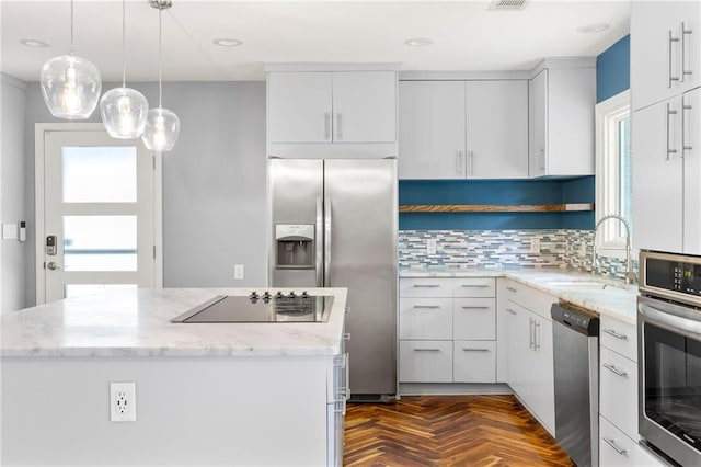 kitchen featuring appliances with stainless steel finishes, a sink, a center island, white cabinetry, and tasteful backsplash