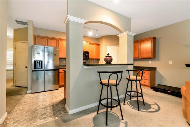 kitchen with ornate columns, stainless steel fridge, and light colored carpet