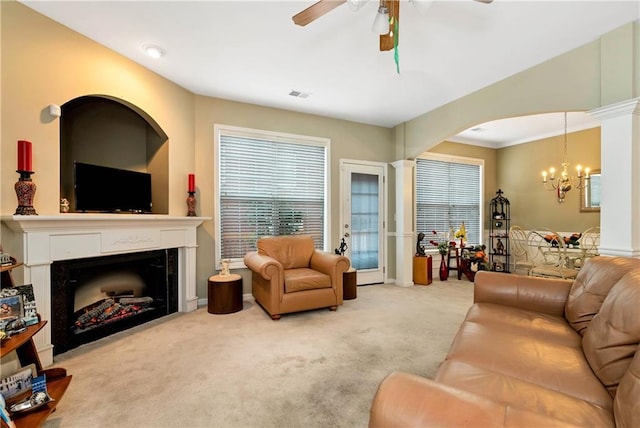 carpeted living room featuring ceiling fan with notable chandelier and crown molding