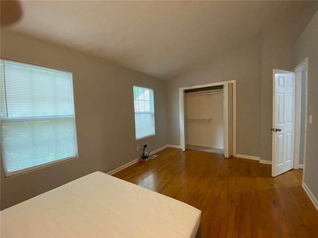 unfurnished bedroom featuring a closet, baseboards, vaulted ceiling, and wood finished floors