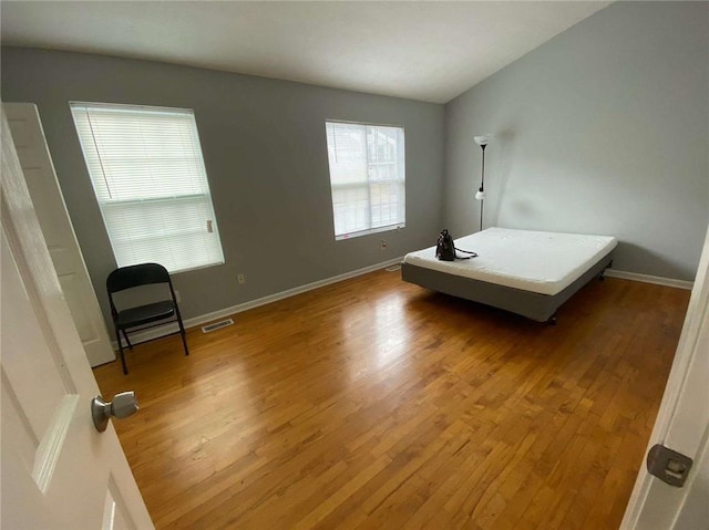 bedroom with visible vents, baseboards, and wood finished floors