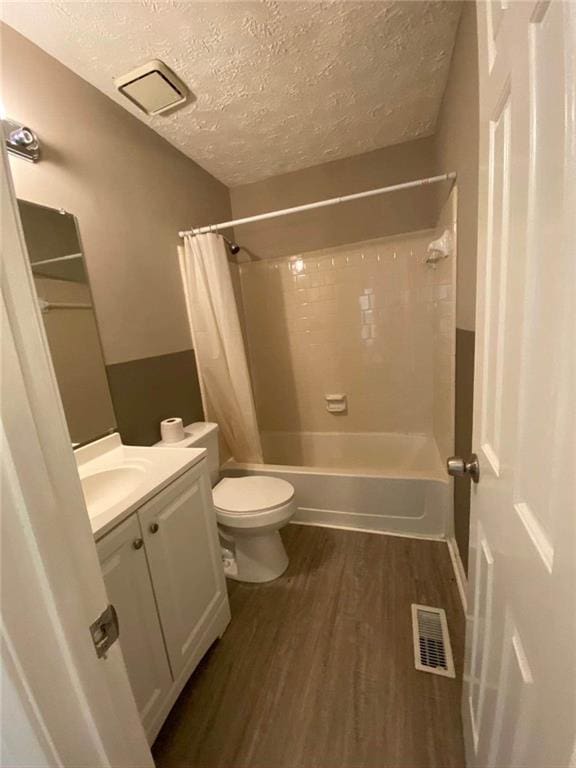 full bath featuring shower / tub combo, a textured ceiling, toilet, visible vents, and wood finished floors