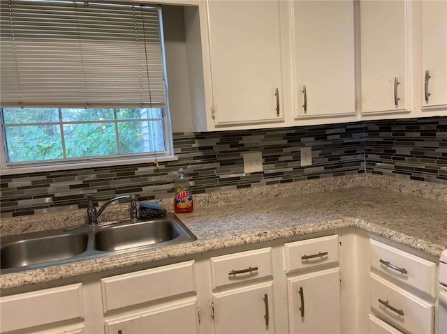 kitchen with white cabinets, tasteful backsplash, light countertops, and a sink