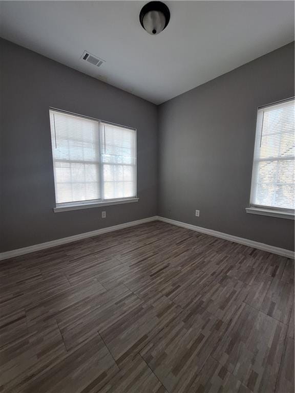 unfurnished room featuring dark wood-type flooring and a wealth of natural light