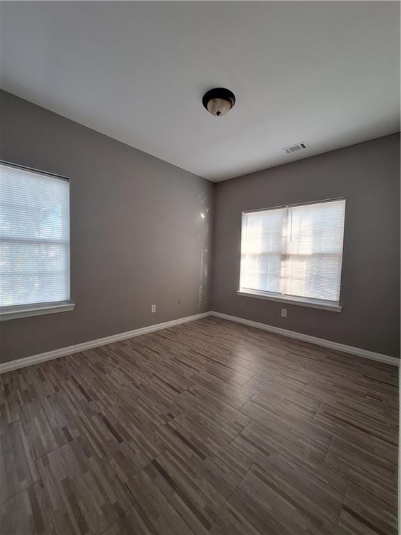 empty room featuring a wealth of natural light and dark hardwood / wood-style flooring