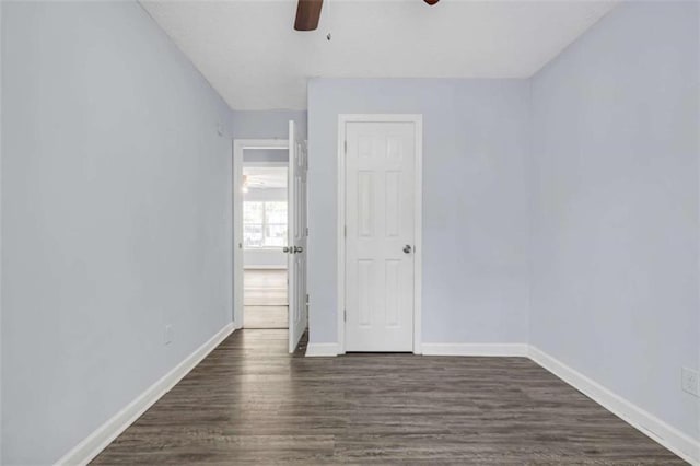 interior space featuring baseboards, a ceiling fan, and dark wood-type flooring