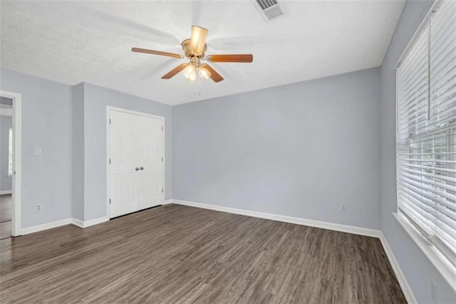 spare room with baseboards, ceiling fan, visible vents, and wood finished floors