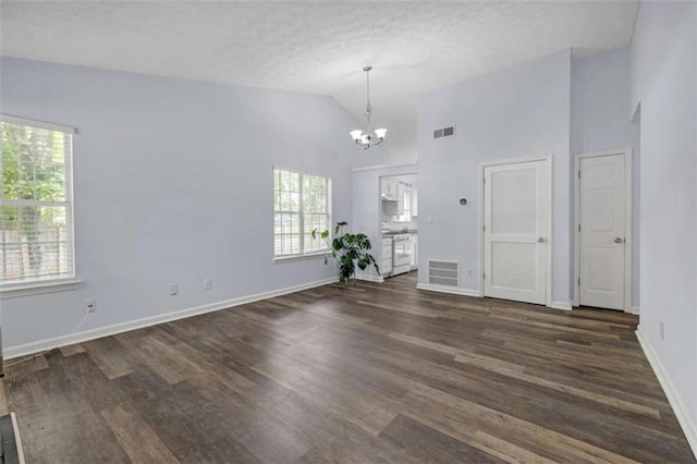 unfurnished room featuring dark wood finished floors, plenty of natural light, visible vents, and a notable chandelier