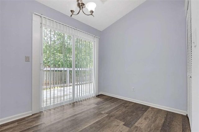empty room featuring vaulted ceiling, a chandelier, dark wood-style flooring, and baseboards