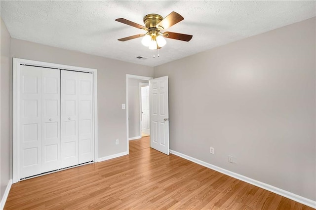 2340 Beaver Ruin Rd Unit 68, Norcross, GA 30071 - unfurnished bedroom featuring baseboards, light wood-style floors, a closet, a textured ceiling, and ceiling fan