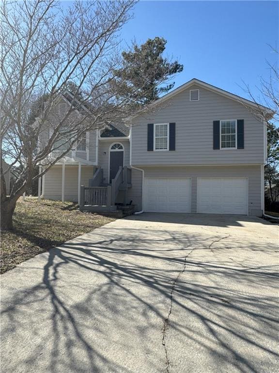 raised ranch featuring a garage and concrete driveway